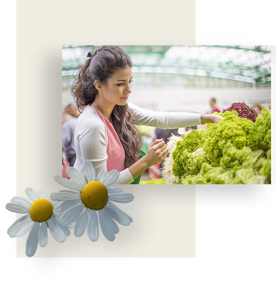 Young woman choosing from various kinds of lettuce while making groceries.